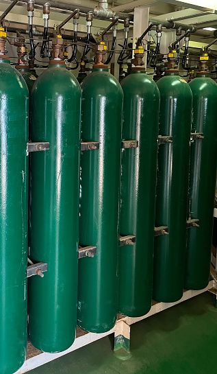 Many oxygen cylinders and argon cylinders with compressed gas secured in the Gas factory warehouse. Green ooxygen tanks for industry. Liquefied oxygen production. Factory