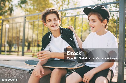 istock Two cute teenagers sit in a skatepark, relax after skateboarding and chat. Boys enjoy their free time in the skate Park, sitting on the ramp. The concept of youth, unity and friendship 1395299648