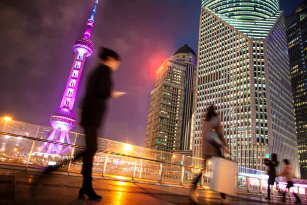 Woman using smartphone walking in Shanghai at night during trip to China