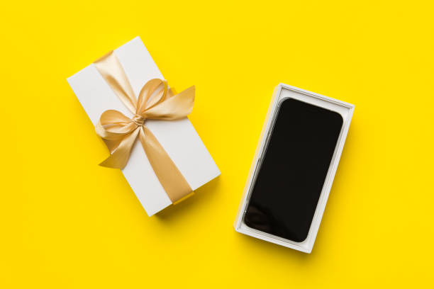 istock Opened gift box with gold ribbon and smartphone on color background, top view. Blank open box packaging mockup , Template for your design - branding mockup 1395303845