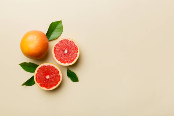 istock fresh Fruit grapefruit with Juicy grapefruit slices on colored background. Top view. Copy Space. creative summer concept. Half of citrus in minimal flat lay with copy space 1395303874