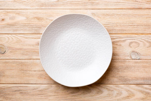 istock Top view of empty light plate on wooden background. Empty space for your design 1395303929