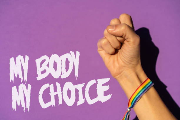 A woman with her fist raised and a text in favor of the legalization of abortion. Protest not to make abortion illegal in the united states, pro-choice, pro-life, on a purple background stock photo