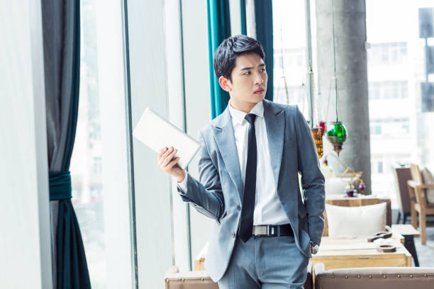 young handsome chinese businessman, wearing a suit standing in the hotel lobby
