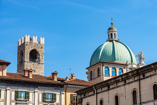 Brescia downtown. New Cathedral of Santa Maria Assunta (Duomo Nuovo), 1604-1825, in late Baroque style and the medieval Tower of the Broletto Palace called Torre del Pegol or Torre del Mercato, XII-XIII century, town square called Paolo VI or Piazza del Duomo (Cathedral square). View from Piazza della Loggia (Loggia town square), Lombardy, Italy, Europe.