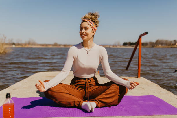 istock Smiling young woman relaxing while doing yoga outdoor 1395308707