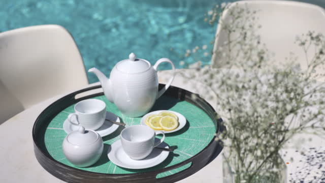 Tea service on table at sunny tranquil poolside