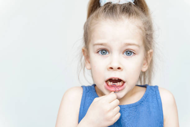 紐を使って緩い歯を引っ張る可愛い怖い女の子 - floss toothpick ストックフォトと画像