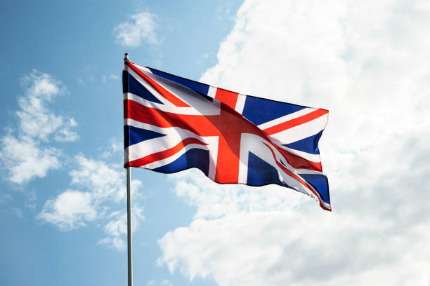 istock Great Britain England  flag waving in the wind over blue sky 1395310229