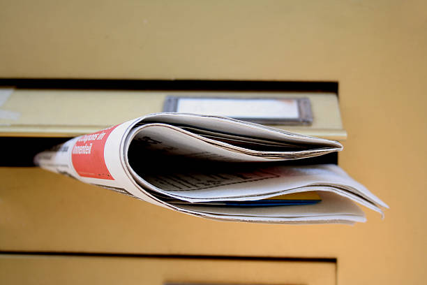 Newspaper in a postbox stock photo