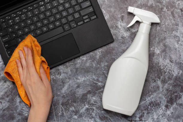 istock Cleaning a laptop keyboard with a rag and cleansing spray bottle mock-up 1395314540