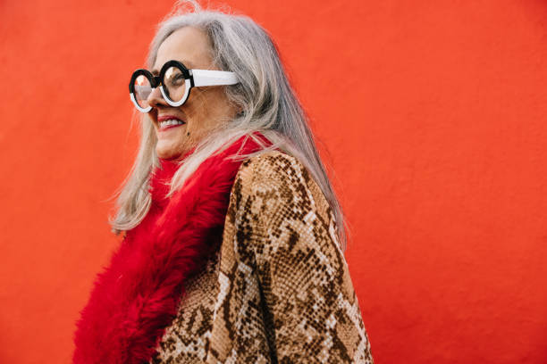 istock Cheerful elderly woman smiling happily against a red background 1395314573