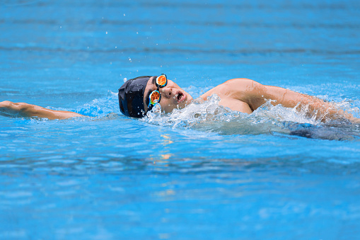 young swimmer in goggles exercising in swimming pool