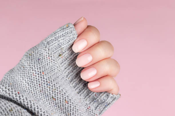 istock Hand in sweater with nude nails on pink background 1395319636