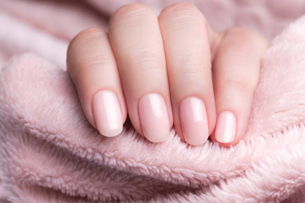 istock Hand in sweater with nude nails on pink textile background 1395319669