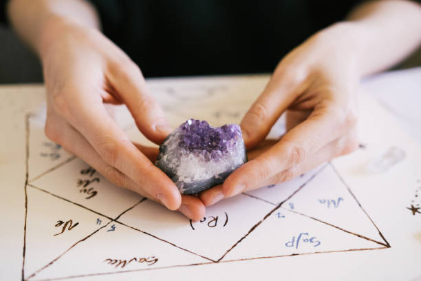 istock Woman holding crystals in her hands. Natal chart and background. 1395320002