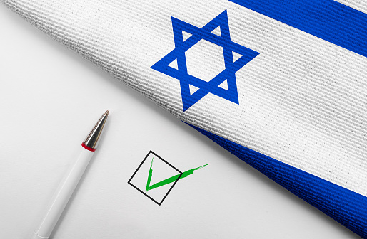 Hands of a Girl and a Boy Form a Heart Shape on the Israeli Flag, with Sunlight Casting a Shadow on the National Flag Hanging from the Balcony.