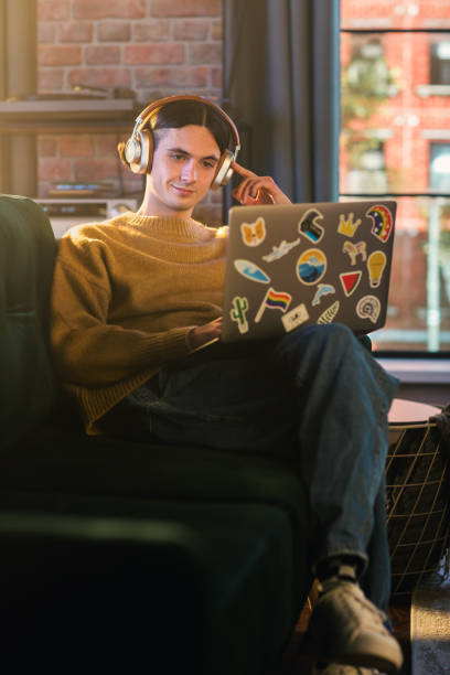 istock Vertical Screen: Young Handsome Man Working from Home on Laptop Computer in Stylish Loft Apartment During the Day. Creative Person Checking Social Media, Browsing Internet. 1395322436