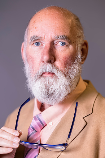 Man in his 70s wearing a fawn jacket, a pink shirt and a tie.