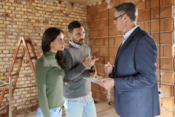 istock Couple talking to building contractor at construction site. 1395323933