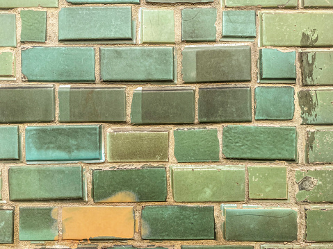 Front view of irregular green tiles covering wall
