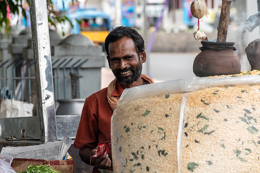 Vellore, Tamil Nadu, India - September 2018: A portrait of a cheerful Indian male street vendor selling snacks and food at his roadside stall.