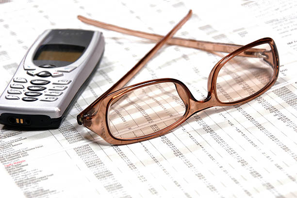 Eyeglasses & Cellphone on financial newspaper stock photo