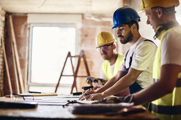 team di operai che esaminano il progetto abitativo mentre lavorano in cantiere. - construction building contractor housing development house foto e immagini stock