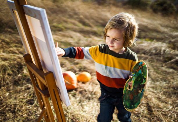 Little boy enjoying while painting in autumn day outdoors.