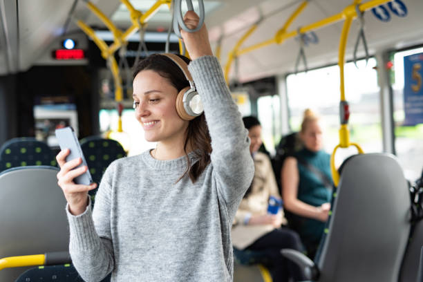 mujer escuchando música por teléfono en el autobús - bus transportation indoors people fotografías e imágenes de stock