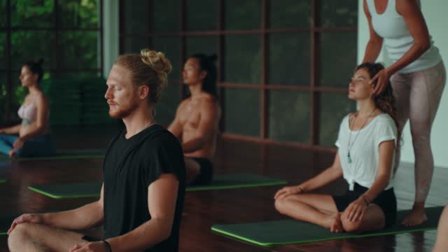 Female yoga teacher improves the posture of her student