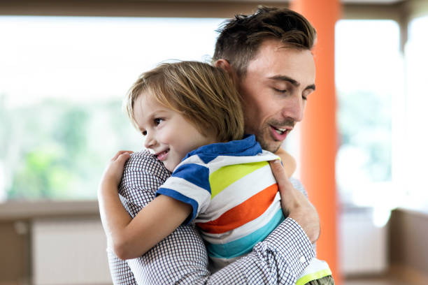 istock Happy little boy embracing his single father at home. 1395326537