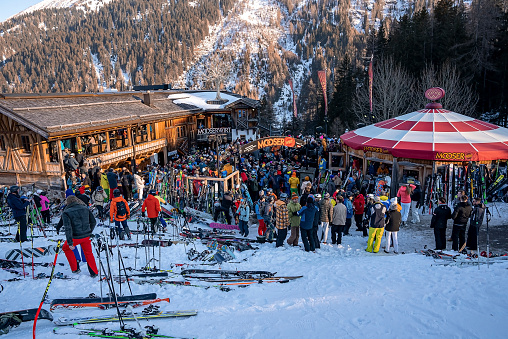 St. Anton am Arlberg. March 10, 2022. Large group of skiers waiting outside mooserwirt. Outdoor after ski restaurant against snow covered mountains. Tourist enjoying on ski mountain during winter.