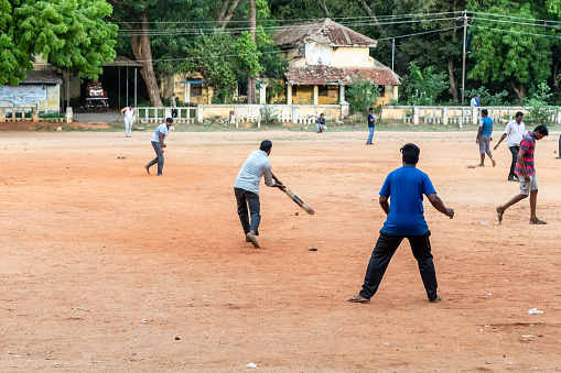 Vellore, Tamil Nadu, India - September 2018: People playing cricket in a play ground in a park in the Vellore Fort complex.