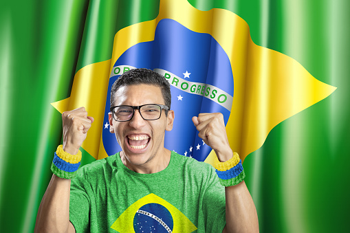 Soccer fan national team of Brazil celebrating goal in front of flag
