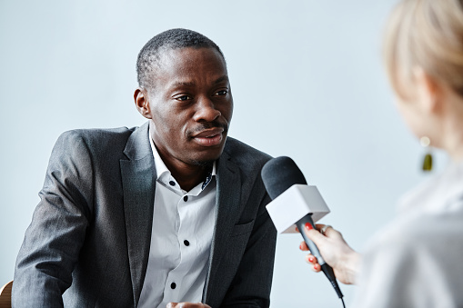 Portrait of black business expert speaking to microphone while giving interivew