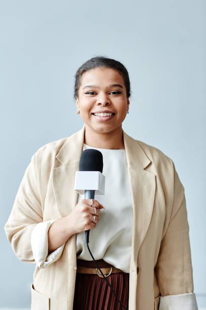 istock Smiling Female Journalist Holding Mic 1395329779