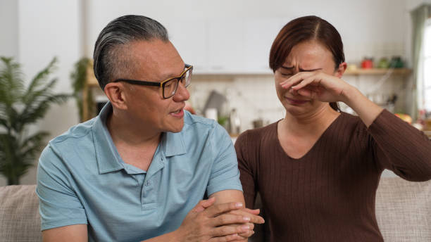 un père asiatique à la retraite attentionné consolant sa fille frustrée et lui tapotant le dos dans le salon à la maison. la femme déprimée pleure et enfouit son visage dans les mains tout en écoutant - pat on back photos et images de collection