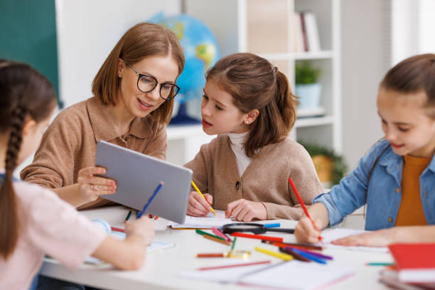 istock Woman with tablet teaching children at school 1395330892