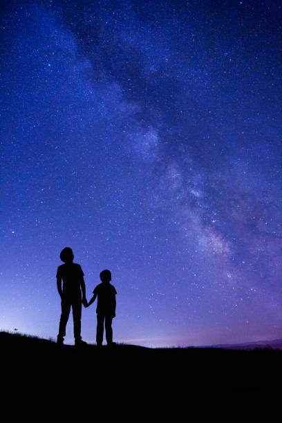 Two boys looking at Milky Way stock photo