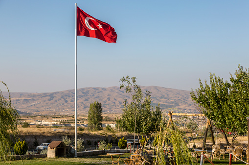 Turkish flag near the horizon in Göreme, Cappadoci. Tourist town with houses in Cappadocia.