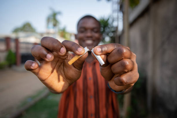 african man breaks a cigarette in two, he does it for his own good, quit smoking concept - quitting imagens e fotografias de stock