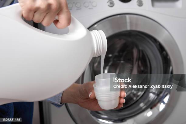 Girl In Tshirt Carefully Pours Transparent Conditioner For Flattening Laundry Stock Photo - Download Image Now