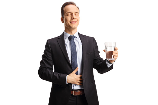 Satisfied businessman with closed eyes holding a glass of water isolated on white background