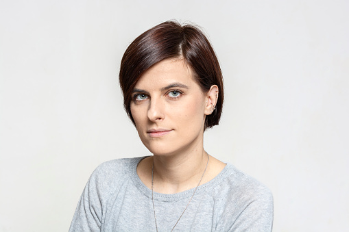 Portrait of serious young woman against white background