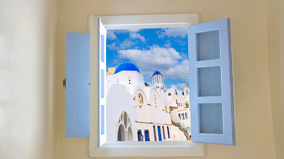 Beautiful view with window  of caldera and classical  of blue dome church  as blue sky background , Oia, Santorini, Greece