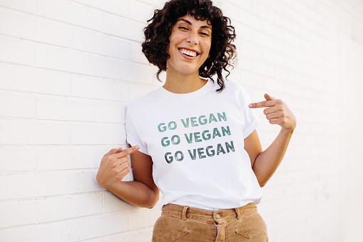 Happy vegan activist smiling at the camera while wearing a shirt with the words 