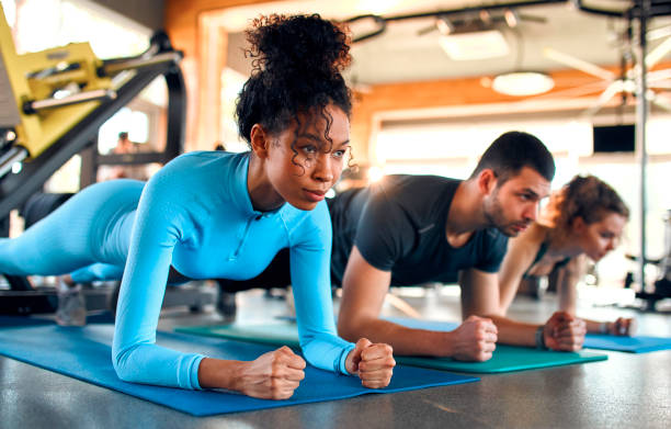 Sports and gym activities Slim women african american and caucasian ethnicity and muscular man in sportswear doing plank exercise on rubber mat in gym club. The concept of sports and recreation. bodyweight training stock pictures, royalty-free photos & images