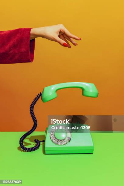 Colorful Bright Image Of Female Hand Holding Oldfashioned Green Colored Phone Handset Falling Down Isolated Over Orange Background Stock Photo - Download Image Now