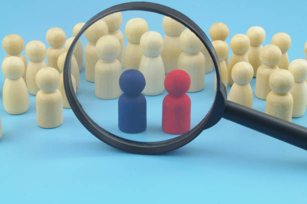 istock Many people figures and two red and blue leaders under magnifying glass. 1395339168
